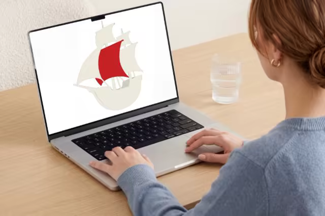 Laptop Mockup Over the Shoulder at a Wooden Desk