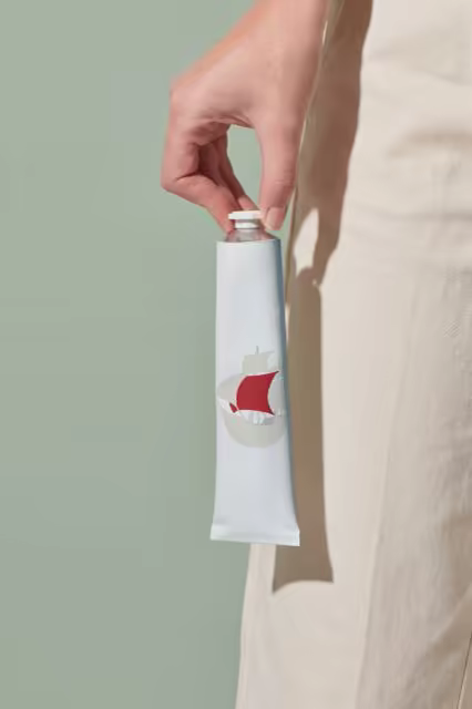 Cosmetic Tube Mockup Held Before a Sage Wall