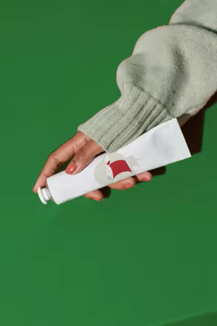 Cosmetic Tube Mockup Held Against Deep Green